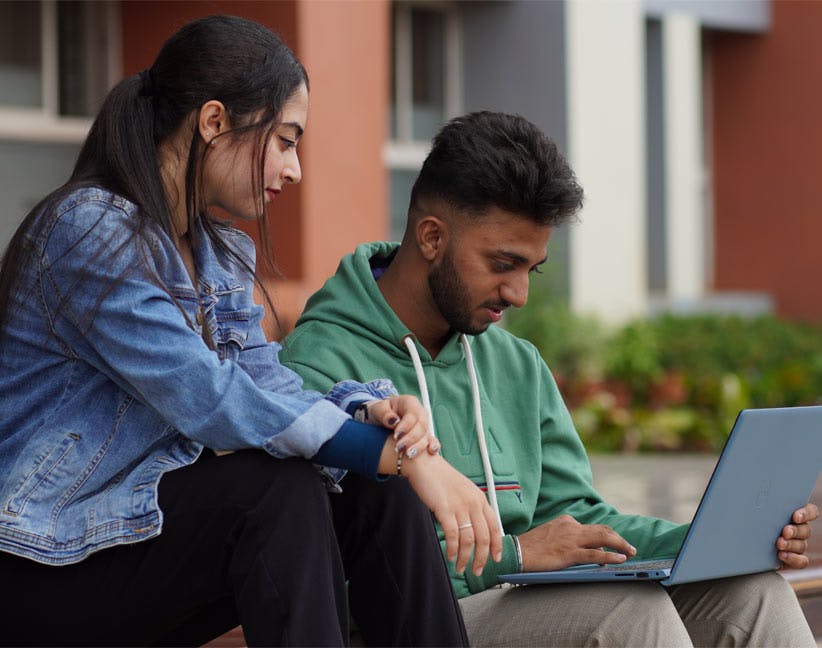 two students sitting with laptop